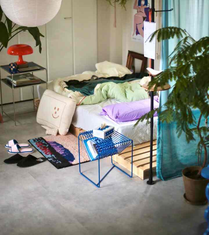 ホワイトとブルーのトーンが調和したワンルームの寝室、ウッド調ベッドと植物が配置されたシンプルな空間