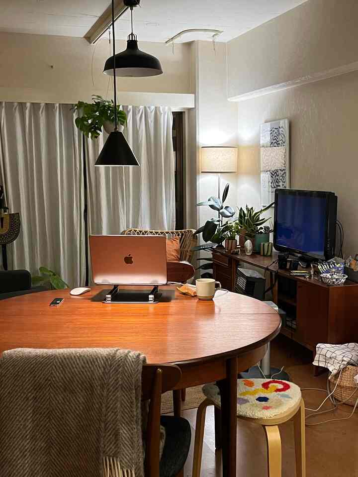 Natural brown and white toned living room featuring a wooden dining table with Apple laptop, creating a cozy home office setup.