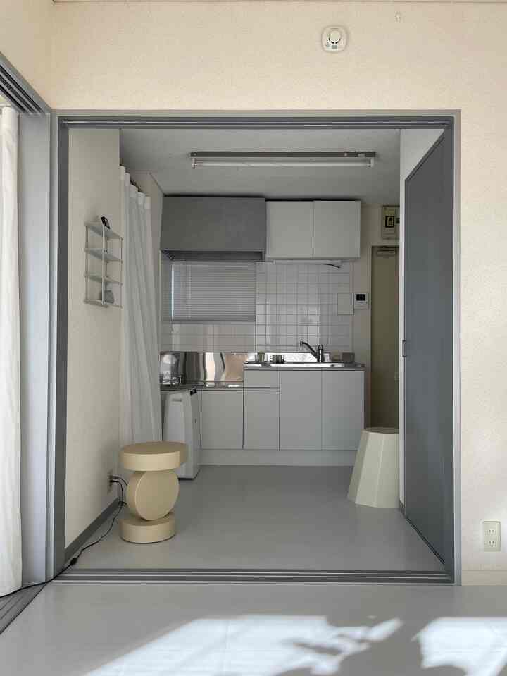 ホワイトとグレーのトーンで構成されたキッチンとスツールが配置されたシンプルでミニマルな空間