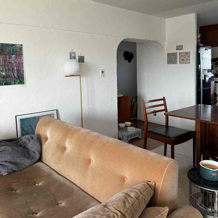 白いテクスチャの壁にベージュのソファと木製のダイニングテーブルが配置された雰囲気のあるリビングダイニング