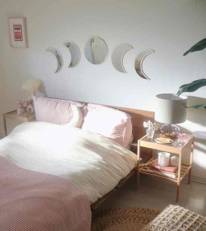 Bright white and brown toned bedroom featuring a wooden bed frame, pink pillows, and white bedding with a natural feel