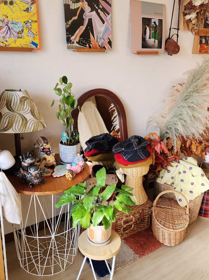 Cozy corner space with brown and natural tones, featuring a side table, plants, and vintage framed art for warm ambiance