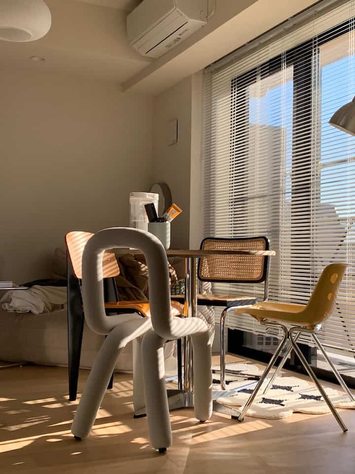 温かみのあるウッドトーンと明るいホワイトが特徴の6畳のモダンダイニングルーム、多様なデザインのダイニングチェアが配置された空間