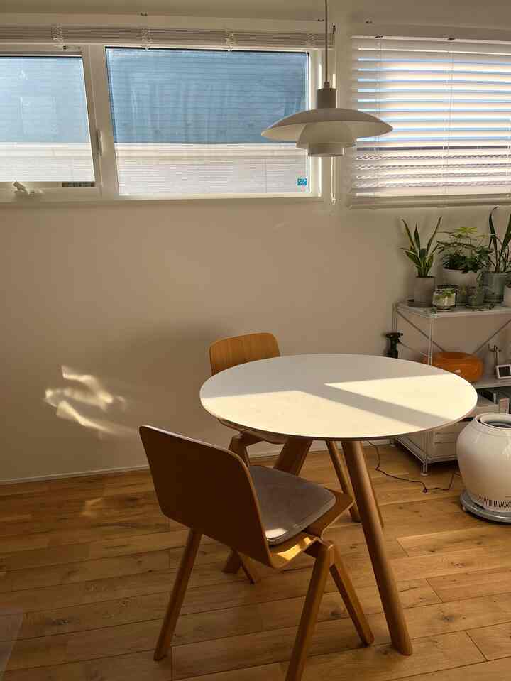 Natural tone dining room with white round dining table and wood tone chairs in a clean setting
