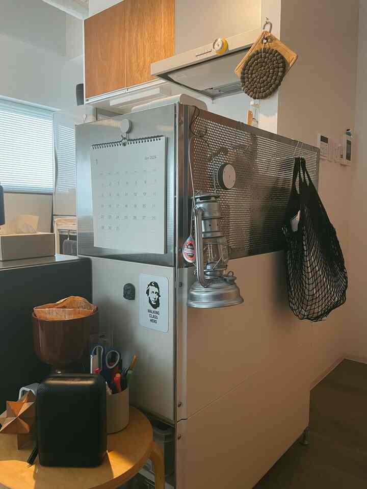 Compact kitchen space with white walls and wood tone cabinets, featuring a refrigerator side and small round table with practical storage ideas