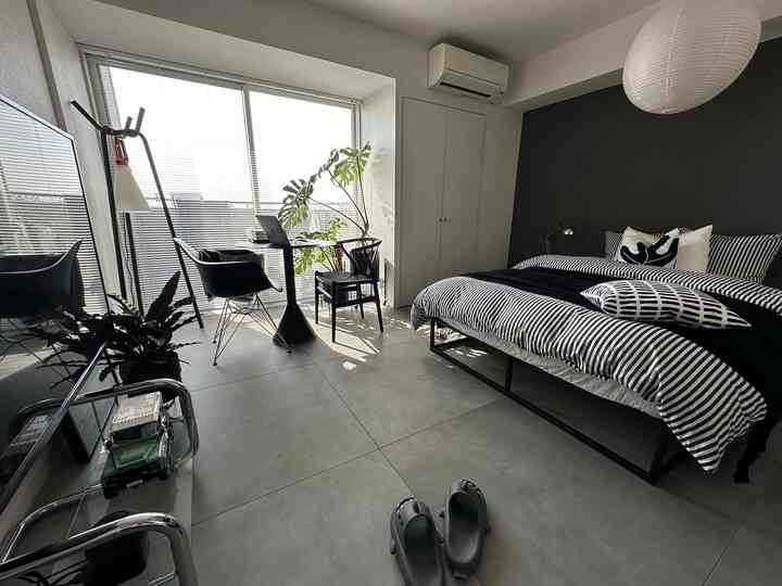 モノトーンの寝室、中央にベッド、窓辺にアームチェアが配置されたモダンで落ち着いた空間