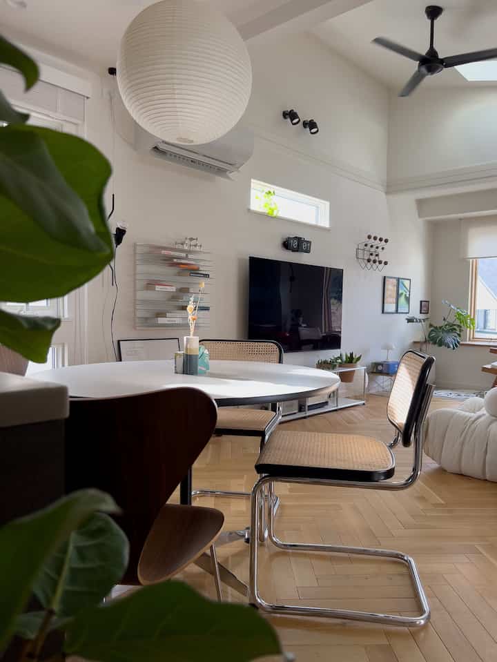 明るいホワイトと木目調のリビング・ダイニング空間、丸いダイニングテーブルとラタンチェアが調和した洗練されたインテリア