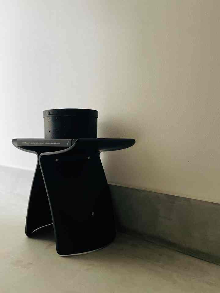 落ち着いた色調の玄関、黒のスツールと丸い小物入れが配置されたシンプルでモダンなインテリア