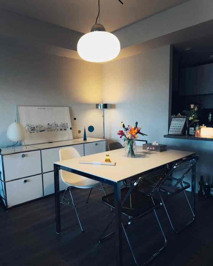 白とダークブラウンの色調のダイニング、シンプルな家具と花瓶が置かれたテーブルのある落ち着いた空間