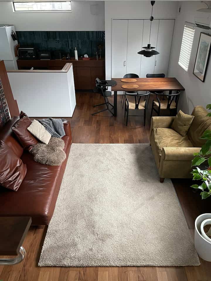 ブラウンとナチュラルな色調のリビング兼ダイニング、レザーソファと木製テーブルが調和する温かみのある空間