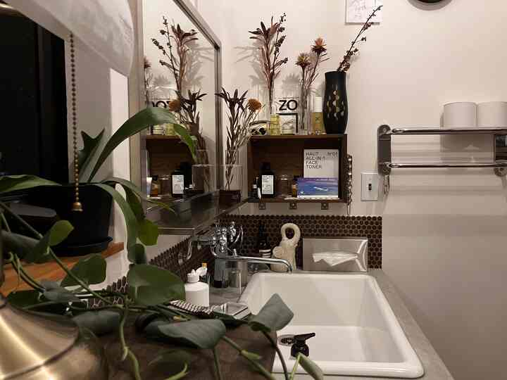 白と茶色のトーンのバスルーム、ステンレス製の小物と大きな鏡が配置された清潔で温かみのあるインテリア