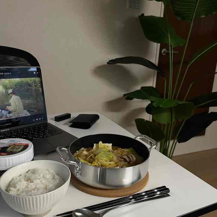 白いテーブルにノートパソコン、鍋、ご飯茶碗が配置された一人暮らしの在宅勤務用ホームカフェ空間