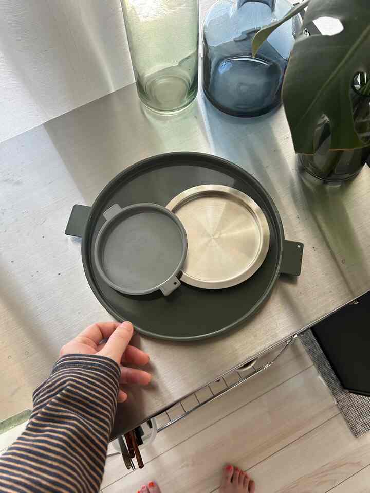 ステンレス製のキッチンテーブルの上にグレーとステンレスのトレイが置かれたワンルームのキッチンスペース