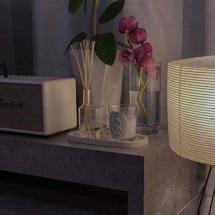 落ち着いたモノトーンのリビング、コンソール上にスピーカー、花瓶、キャンドルが配置されたシンプルな空間