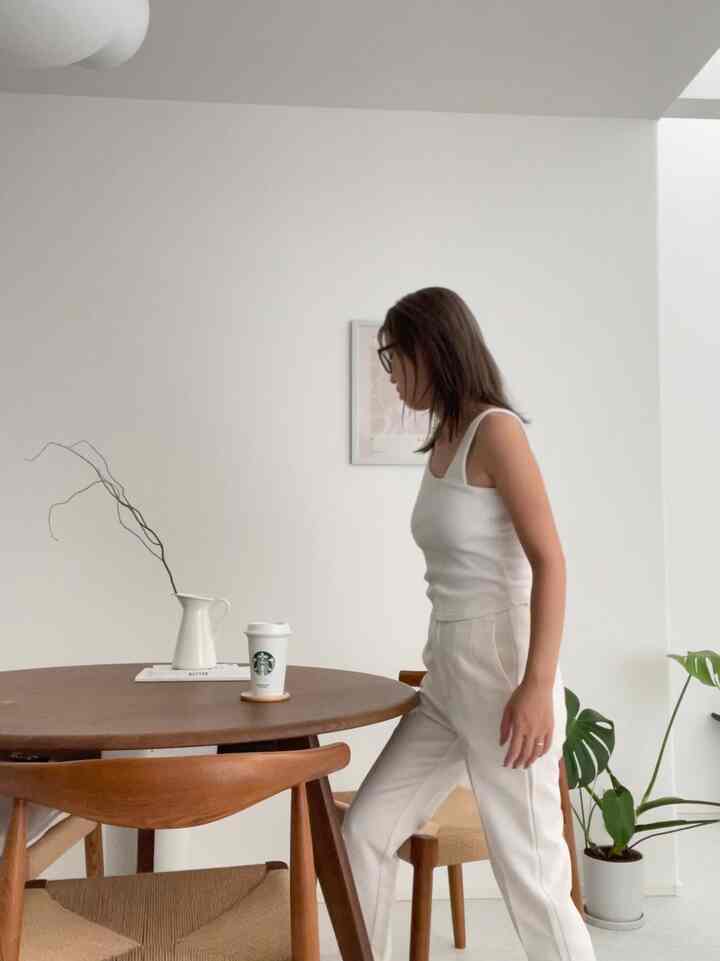 白い壁と木目調の丸いダイニングテーブル、植物と花瓶が配置されたナチュラルなダイニングルーム