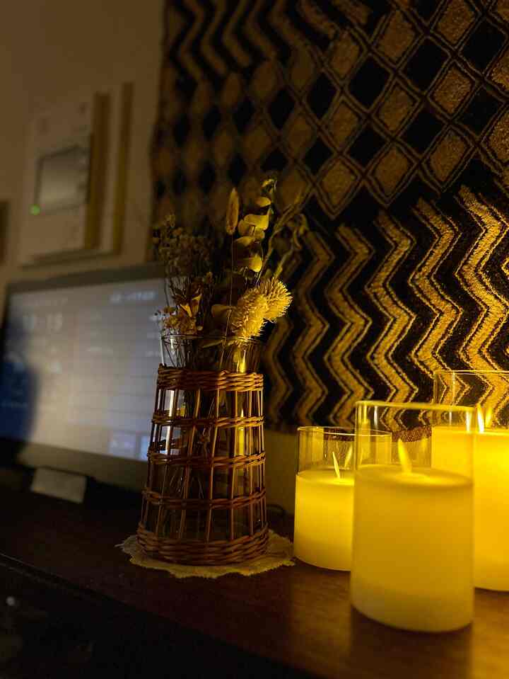 温かみのある黄色い光が映えるヴィンテージ風リビング、ラタンの花瓶とLEDキャンドルが配置された雰囲気のあるインテリア