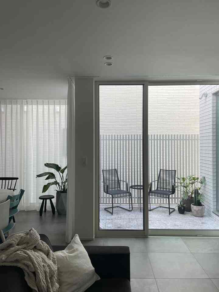 White and gray toned living room with balcony, featuring simple stools and plants in a natural atmosphere