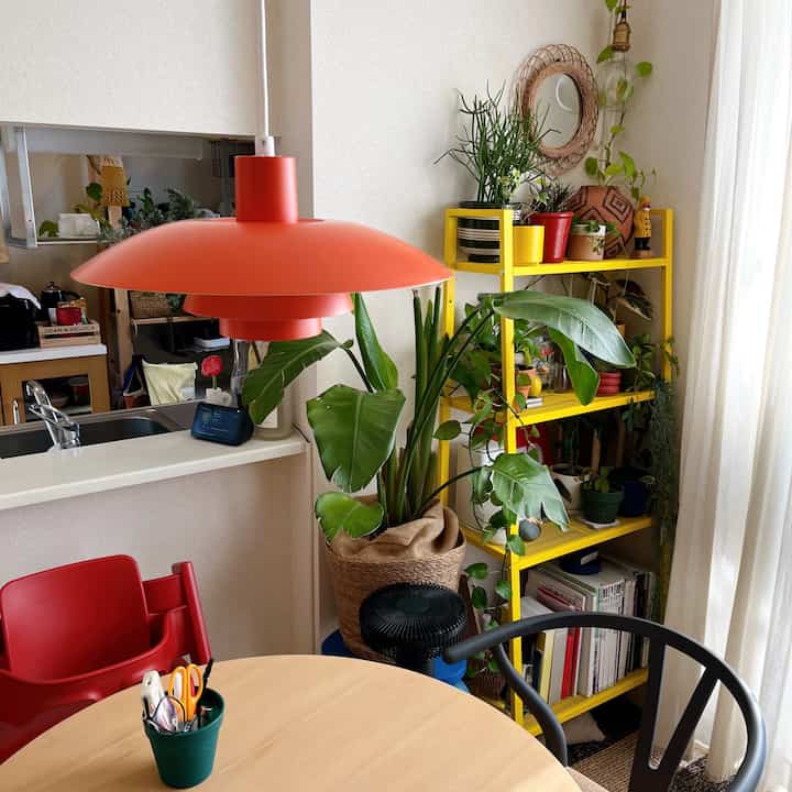 Natural-toned dining room with red pendant light and abundant plants creating a cozy atmosphere