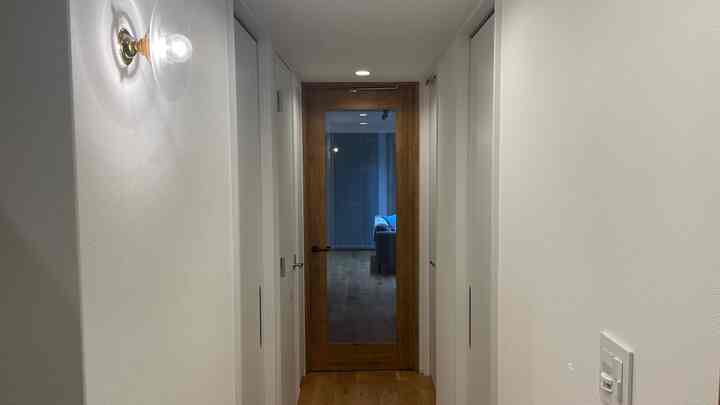 ナチュラルカラーとシンプルな玄関廊下、かわいいブラケットライトが配置された清潔感のある空間