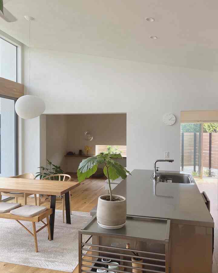 Beige-toned kitchen and dining room featuring wooden dining table, chairs, and stainless steel kitchen cart in a natural setting