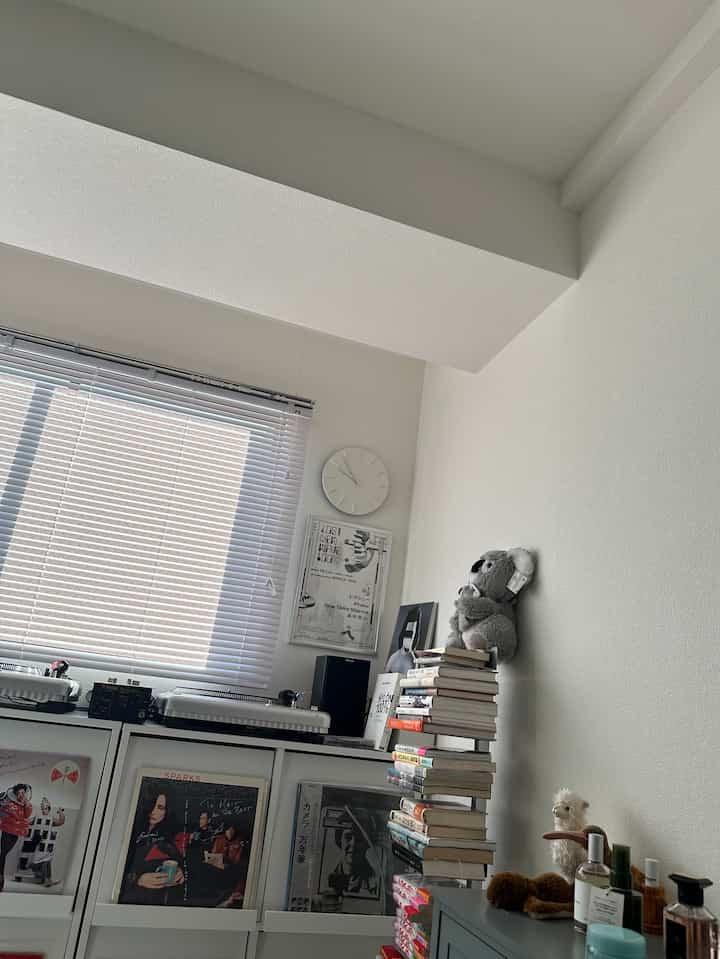 White-toned study featuring bookshelves, wall clock, and blinds in a neat interior