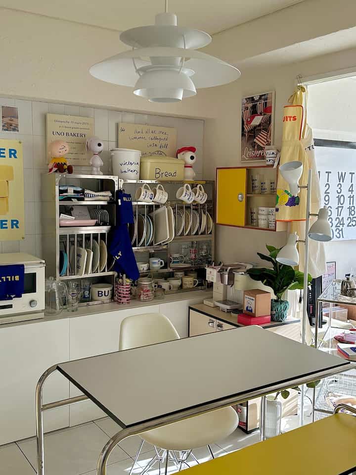 Bright white and yellow tone dining room featuring stainless kitchen rack and pendant light creating a natural atmosphere