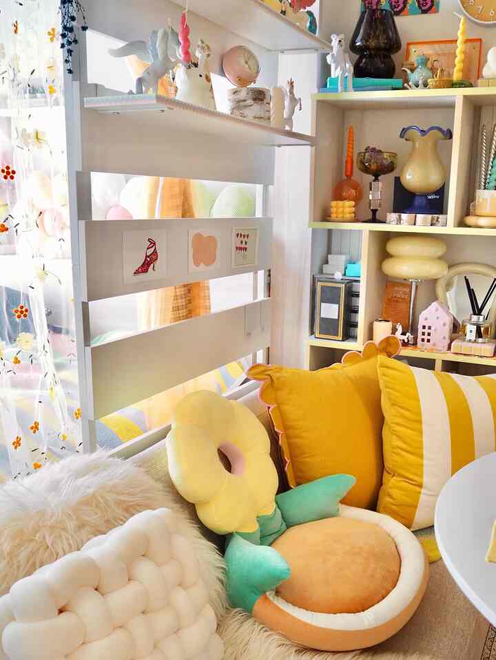 Bright yellow and white Nordic-style living room featuring various unique cushions and charming decor creating a cozy space