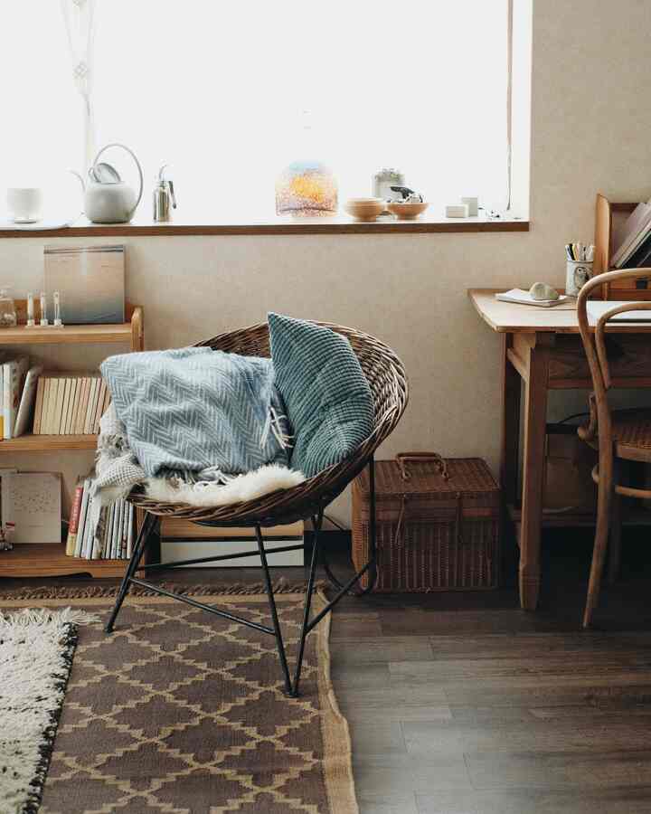 Natural-toned living room featuring a rattan chair, wooden desk, and rug with a cozy atmosphere