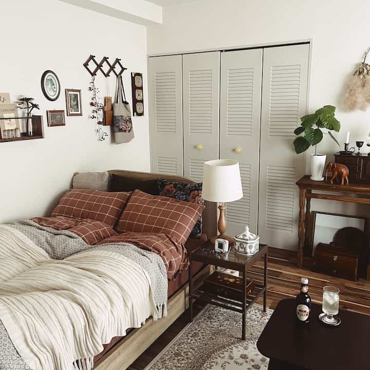 Beige and brown toned bedroom featuring a bed, side table, and table lamp with a warm natural retro ambiance
