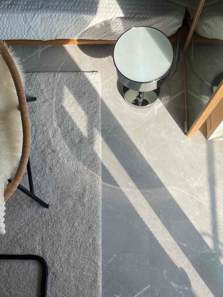 ナチュラルな木目調とグレーのラグがある6畳の寝室の床にモダンなスツールが配置された空間