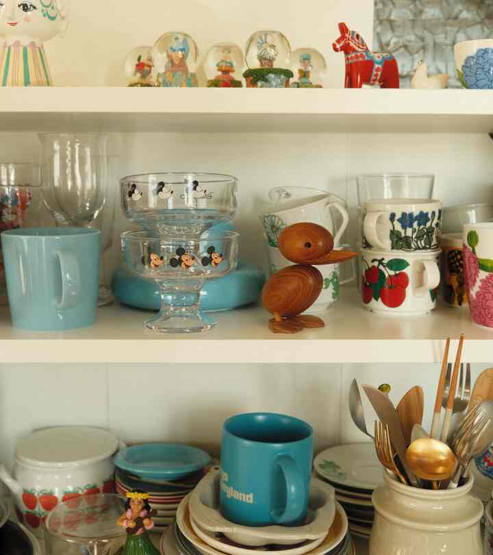 白い棚に様々なキッチン用品と青いマグカップ、木製のアヒルの置物が配置された雰囲気のあるキッチンインテリア