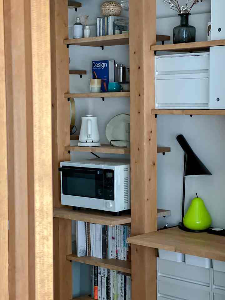Natural color wooden shelves with white appliances arranged in a cozy kitchen space