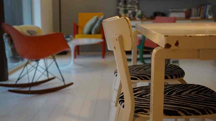 Bright white and orange toned Nordic dining room featuring vintage furniture and a rocking armchair with a simple atmosphere
