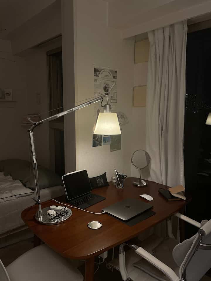 Warm wood-toned table and white curtains in a single household home office and home cinema space