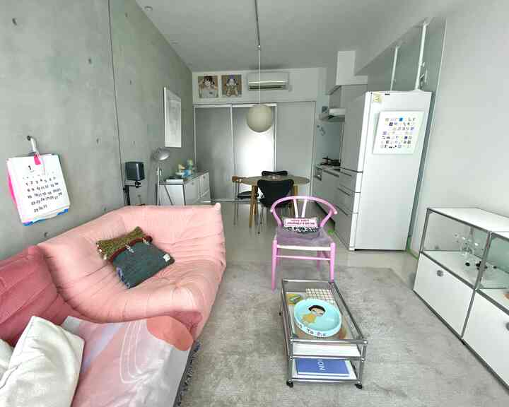 White and pink toned living room and kitchen space featuring a round dining table and pink sofa with a modern clean interior