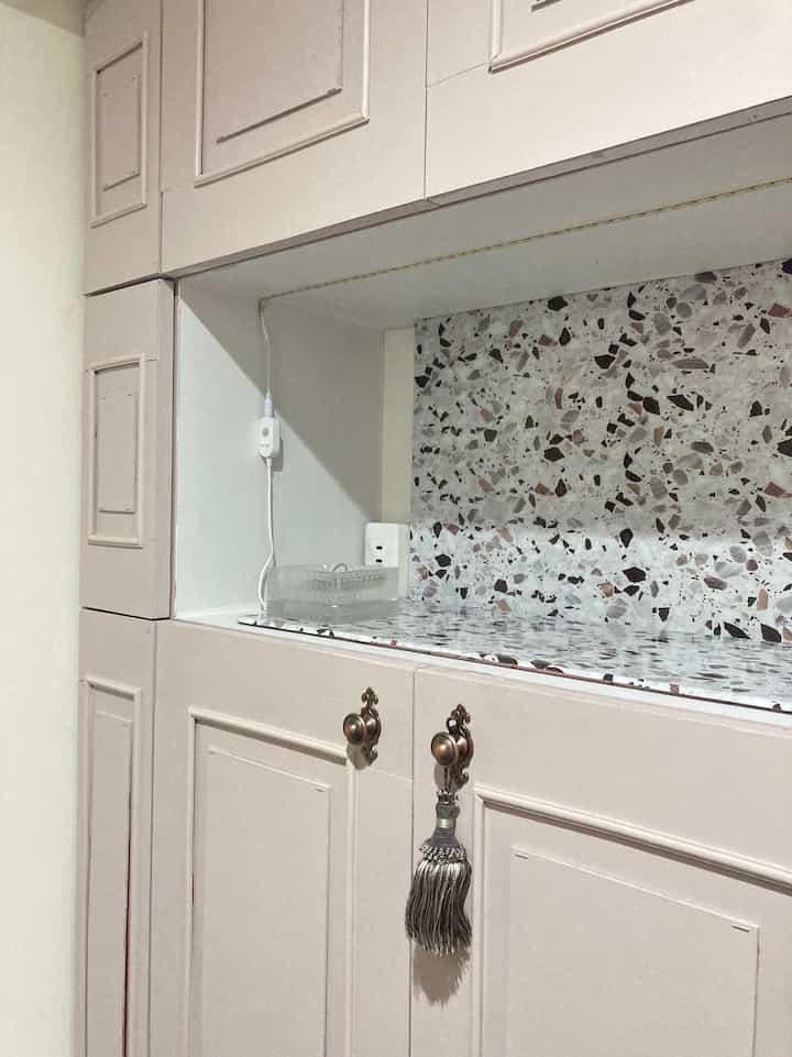 ベージュ色調の玄関シューズラック、中央にブロンズのアンティーク取っ手とタッセルが飾られた整った空間