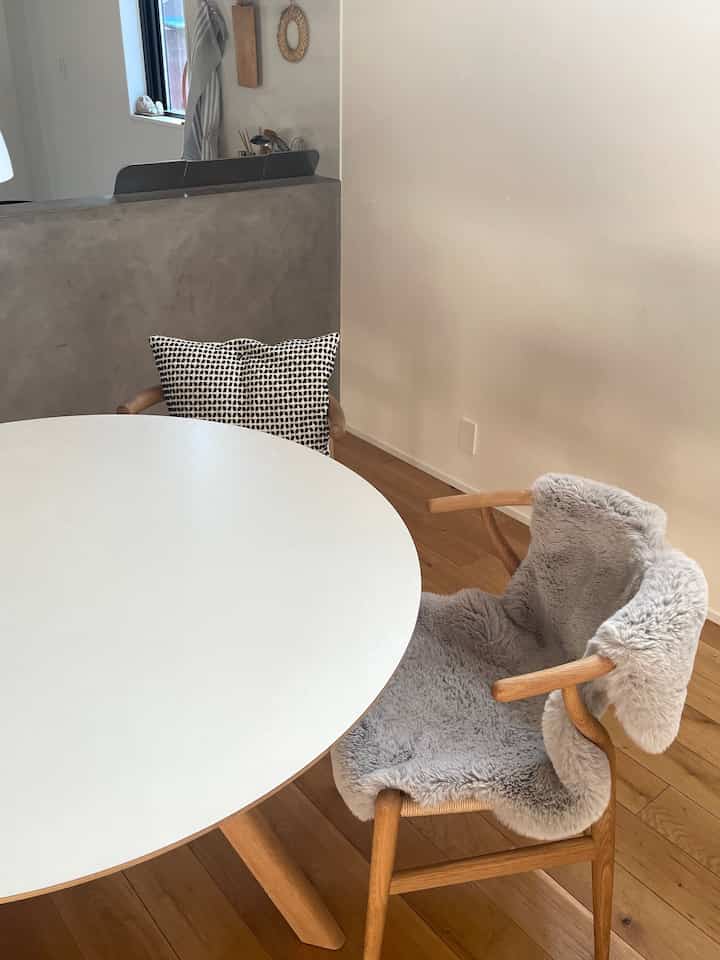 白い丸テーブルと木目調の椅子が配置された、ナチュラルでシンプルなダイニングの印象的な空間