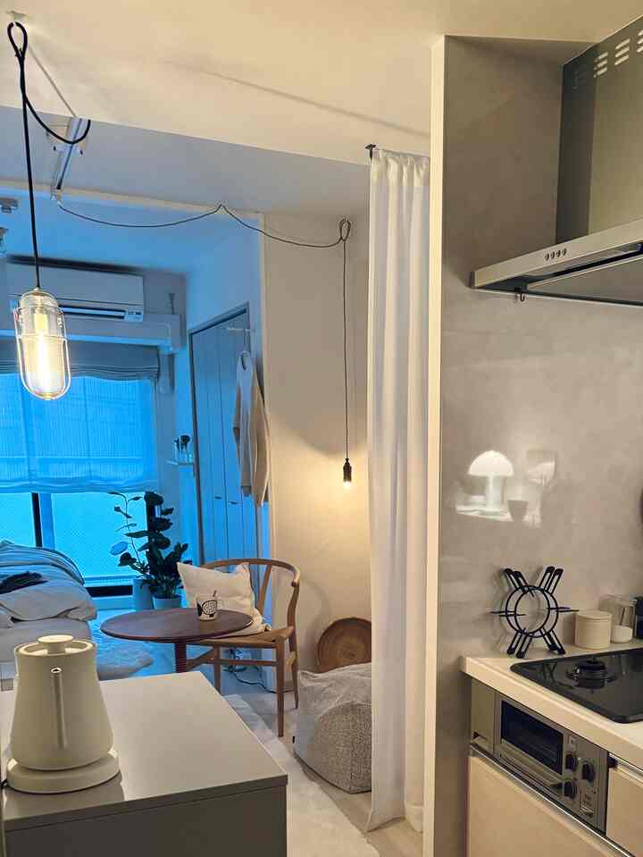 White and natural toned compact kitchen space for a single household featuring a small dining table, chair, and plant with cozy atmosphere