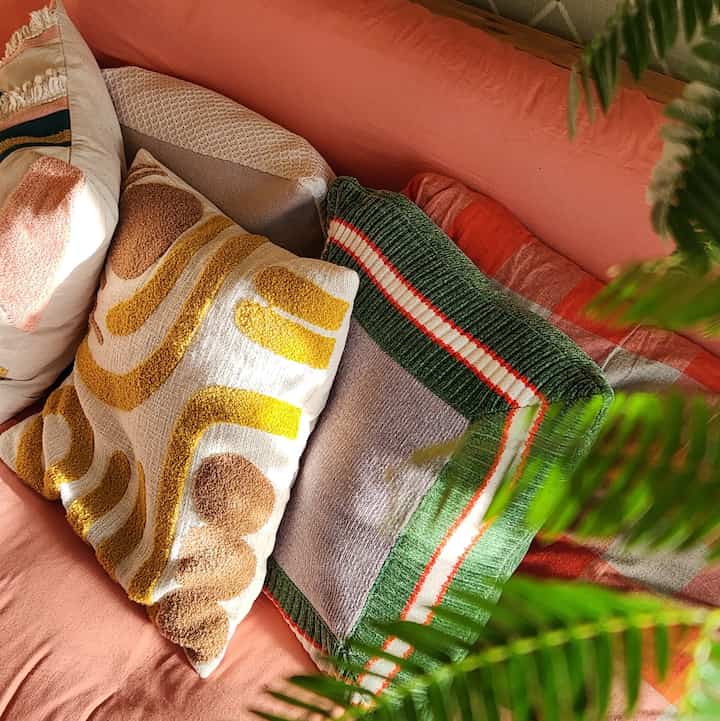 Cozy space featuring an orange-toned sofa with green and beige patterned cushions