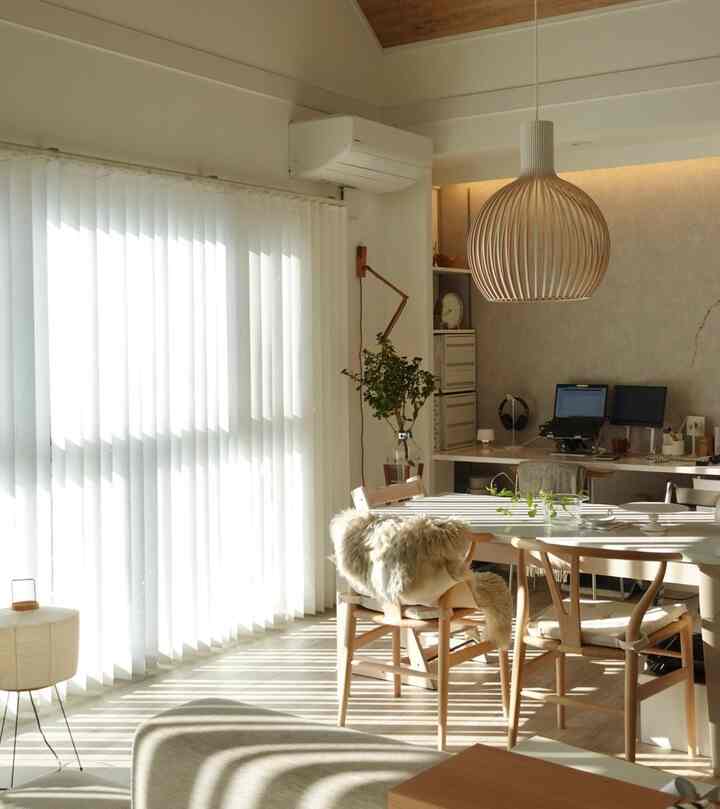 Bright white and wood tone dining room with workspace, warmly illuminated by soft natural light creating a cozy atmosphere