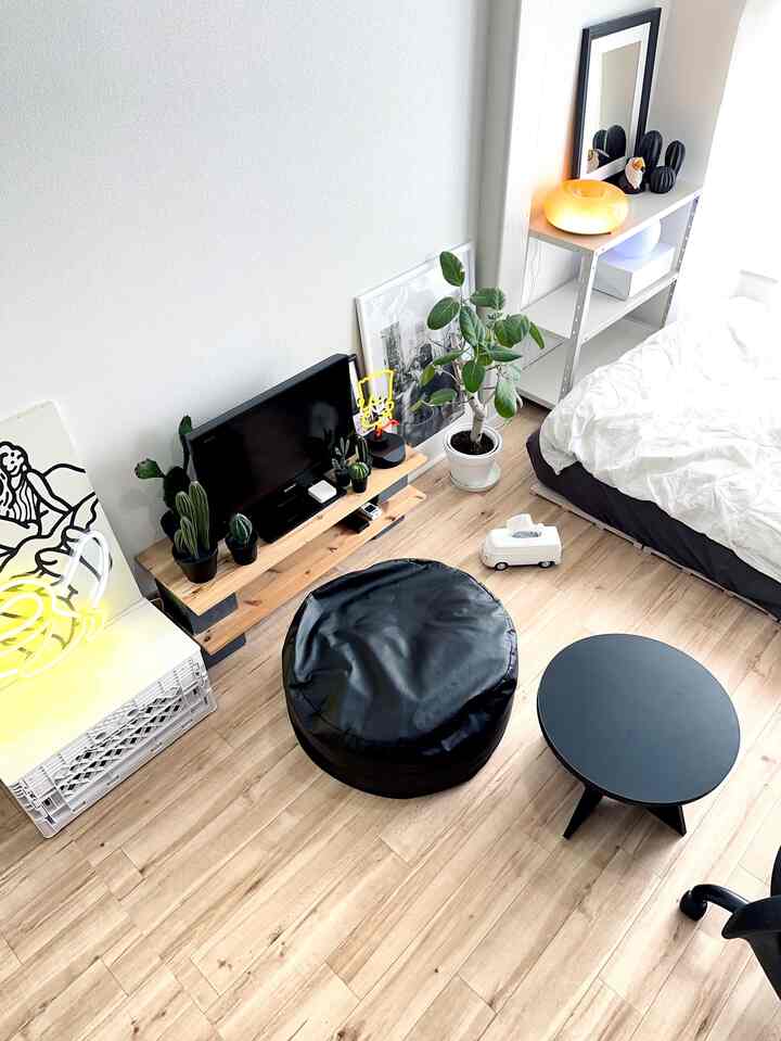 白と木目調が調和するワンルームの寝室、ビーンバッグソファとコーヒーテーブルが配置されたミニマルな空間
