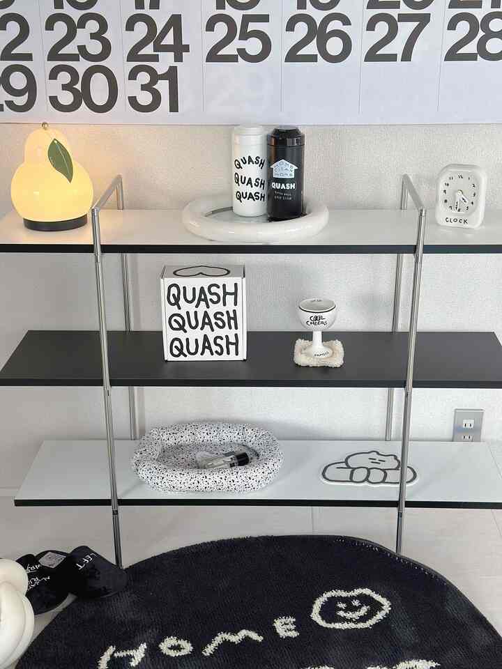 黒と白のトーンで統一されたモダンなワンルーム、黒い棚とかわいい小物が整然と配置された印象的なインテリア