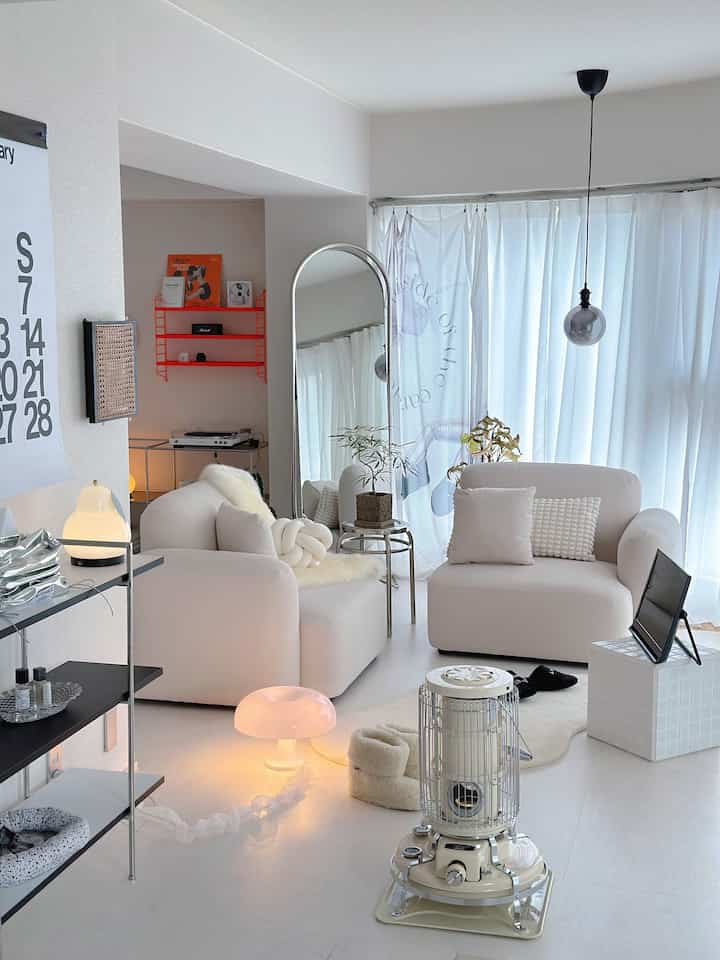 白を基調としたリビング、2台のソファとヴィンテージのストーブが配されたシンプルで落ち着いた空間