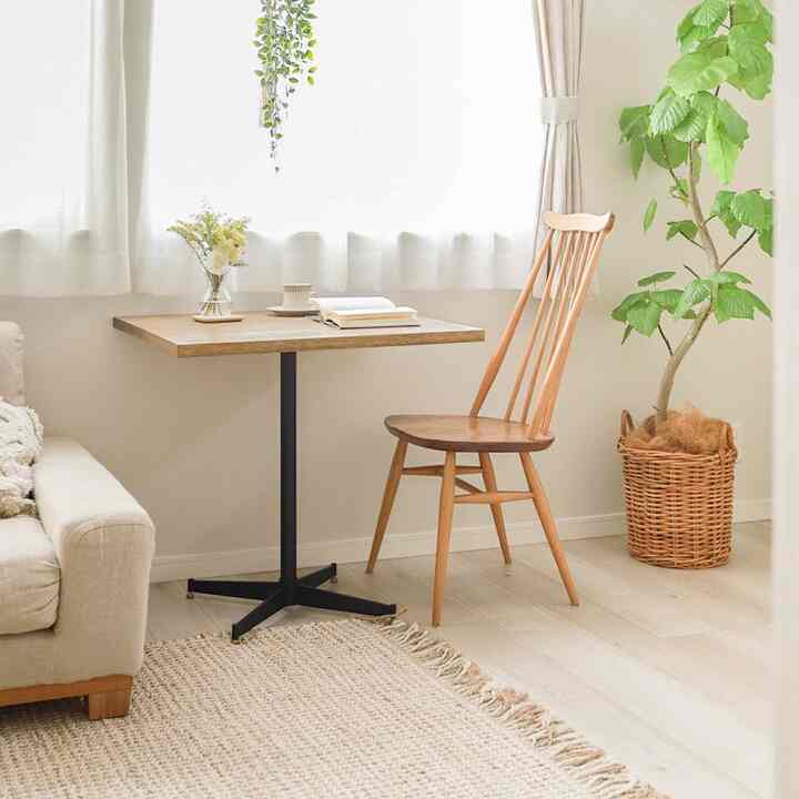 ベージュと木目調の小さなホームオフィス空間、カフェ風のテーブルと椅子、大きな植物とラグが配置された雰囲気のあるインテリア