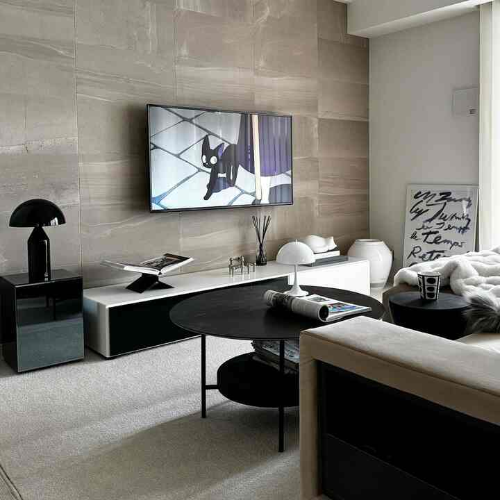 Natural modern living room with beige sofa, black round coffee table, and white TV stand with minimalist decor