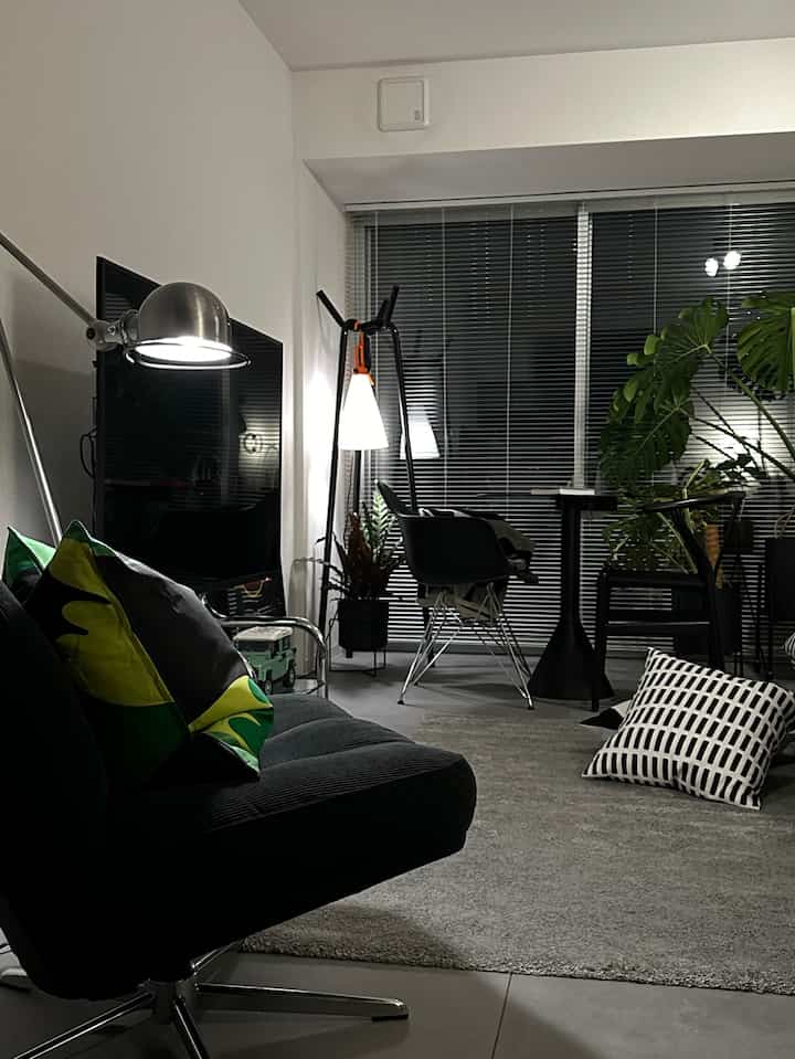 Modern styled living room in black and green tones featuring armchair, floor lamp, and large plant