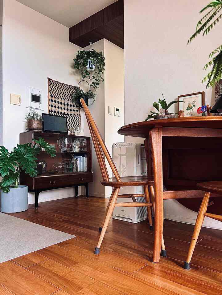 温かみのある木目調とヴィンテージスタイルのダイニング、キャビネットとダイニングチェアが配置されたナチュラルな空間