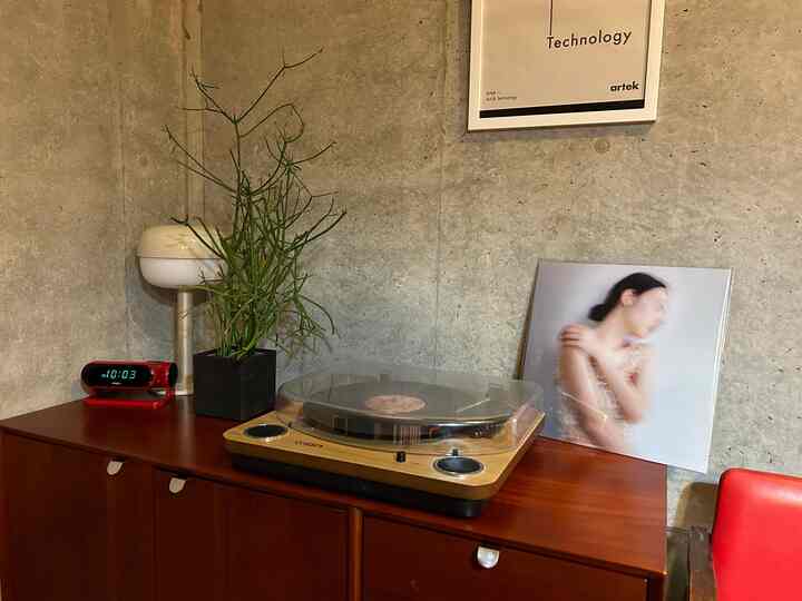 ナチュラルトーンのリビング、レコードプレーヤーと植物が配置されたモダンなコンソールテーブルのある雰囲気のあるインテリア
