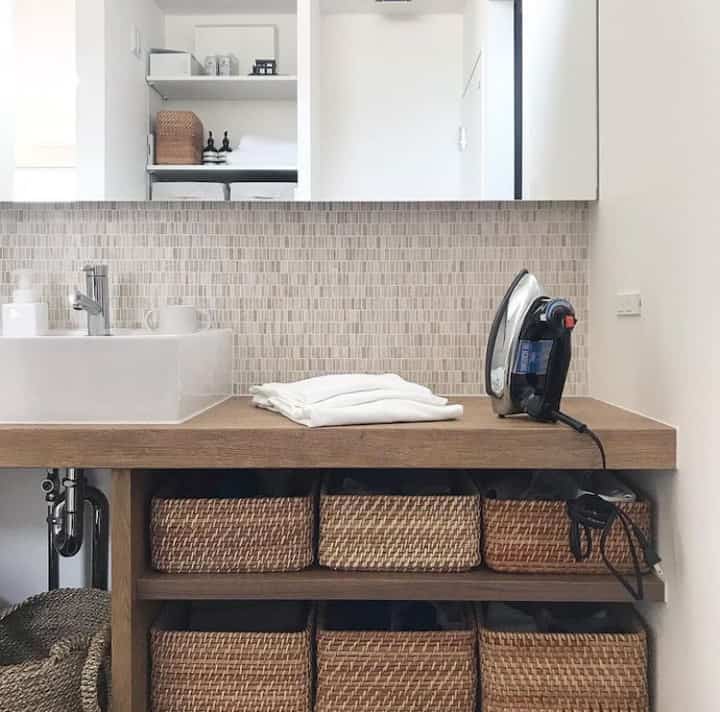 ナチュラルトーンのバスルーム、ラタンバスケットと木製カウンターが調和した清潔感のあるインテリア