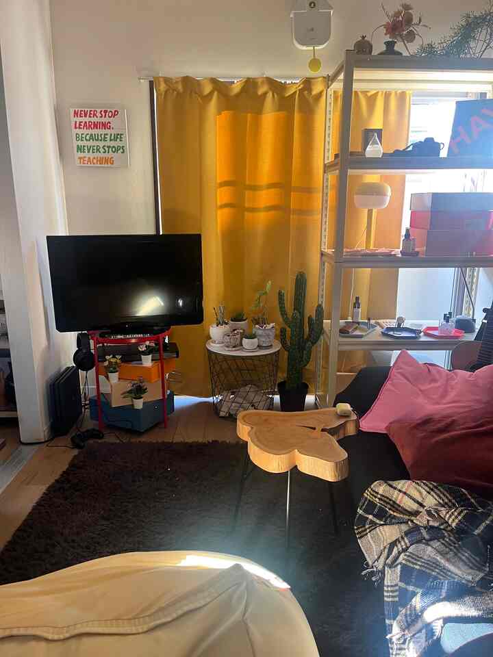 Warm yellow curtains in a cafe-style living room featuring black sofa, wooden table, plants, and cozy décor
